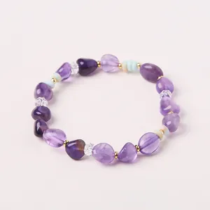 Detailansicht eines Amethyst-Armbands mit unregelmäßigen lila Steinen und goldenen Perlen