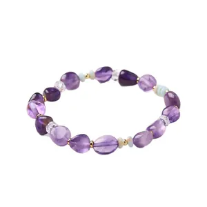 Armband aus unregelmäßigen Amethystperlen mit goldenen Zwischenstücken auf weißem Grund