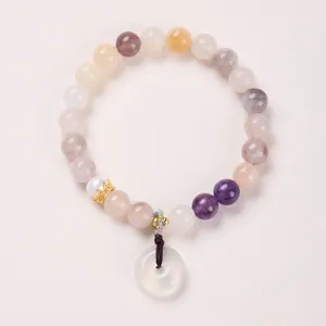 Detail of 8mm natural jade beads bracelet with gold crown charm and translucent donut pendant