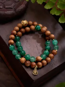 Detail van een dubbele armband van hout en jade met gouden kraal en pompoenvormige hanger