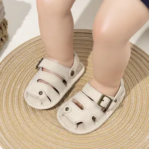 Close-up of baby boy closed-toe sandals in beige PU leather with soft sole on woven mat
