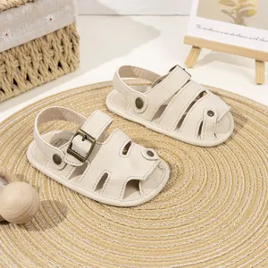 Detail of closed-toe baby sandals in soft beige PU leather with bronze metal buckle details
