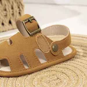 Detailed view of baby leather sandals featuring cut-out design and bronze metal buckle