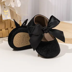 Detail of baby Mary Jane shoes with glitter fabric, satin bow and anti-slip sole