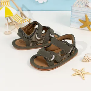 Detail of baby boy camo sandals featuring durable hook and loop straps in a beach scene