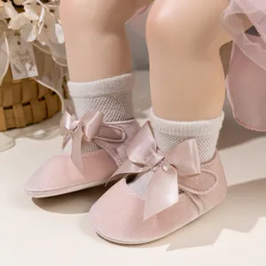 Detail of pink velvet baby Mary Jane shoes with satin bow and velcro strap on a model