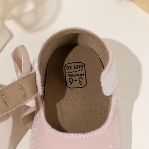 Detail view of pink velvet baby shoes with satin bow and size marking for 3-6 months