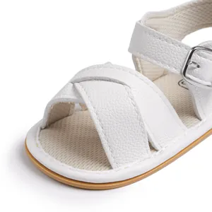 Detailed macro of baby sandals featuring white pebbled leather and silver metal buckles