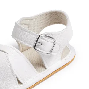 Detail of white baby sandal showing leather texture, metal buckle and mesh lining
