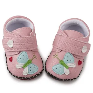 Close-up of pink leather baby shoes with butterfly embroidery and velcro strap design