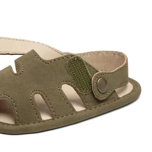 Detail of olive green suede baby sandal with hook-and-loop strap and metal button