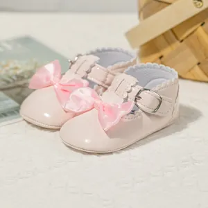 Details von rosa Lackleder-Babyschuhen mit großer Schleife und gewelltem Rand