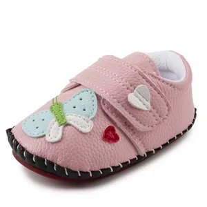 Detail of pink baby walking shoe with butterfly and heart patches and velcro closure