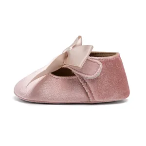 Detailed side view of pink velvet baby shoes with a soft sole and satin ribbon bow