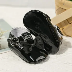 Detail von glänzenden schwarzen Baby-Mary-Janes mit Schleife und rutschfester weicher Sohle