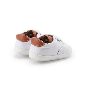 Detailed back view of white canvas baby walking shoes with brown leather heel accents