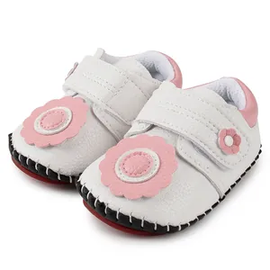 Détail de chaussures bébé en similicuir blanc avec fleurs roses et velcro