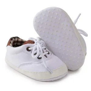 Close-up of white canvas baby shoes featuring non-slip soft soles and brown leather heel detail