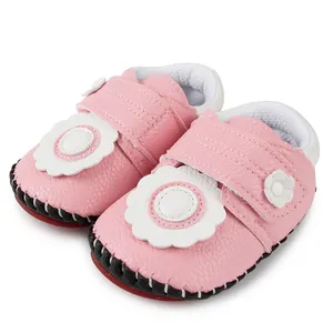 Détail de chaussures de marche bébé roses avec fleur blanche et semelle rouge antidérapante