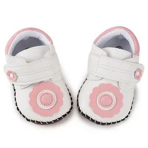 Detail of white infant baby shoes with soft pink floral accents and Velcro strap