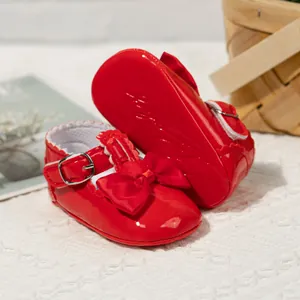 Detail von roten glänzenden Lackleder-Babyschuhen mit Satinschleifen und weicher Sohle