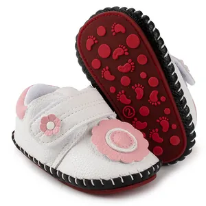 Detail of baby walking shoes showing pink flower deco and red non-slip rubber sole