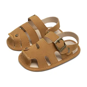 Detail of tan suede baby sandals featuring a closed-toe design and bronze metal buckle