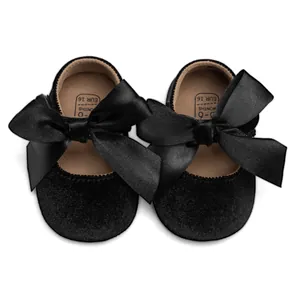Close-up of black velvet baby Mary Jane shoes with ribbon bow and size 16 marking