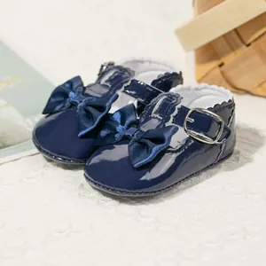 Detail von dunkelblauen Lackleder-Babyschuhen mit großer Schleife und T-Riemen-Metallschnalle