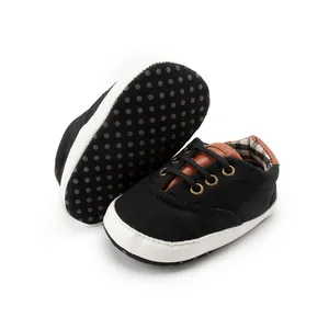 Detailed macro view of black baby canvas shoes with plaid lining and anti-slip dotted soles