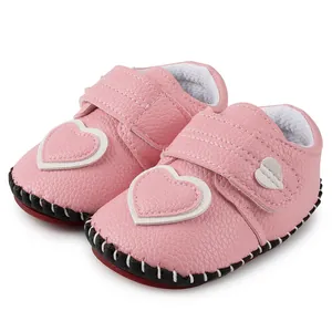 Détail de chaussures de marche roses pour bébé avec texture cuir et décorations cœur