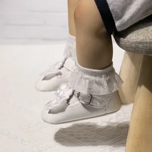 Detailansicht der weißen Baby-Mary-Janes mit Seidenschleifen und Spitzensocken