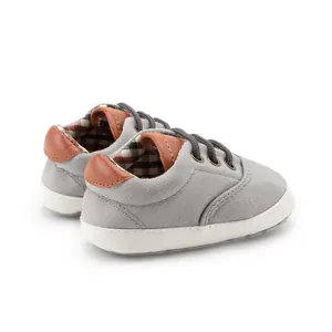 Detail of grey canvas baby shoes with soft soles and classic brown checkered lining