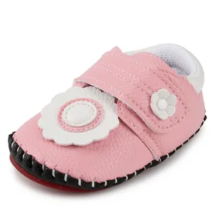Close-up of pink leather baby shoe with white flower detail and non-slip rubber sole