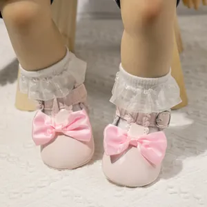 Rosa Lackschuhe für Babys mit Satinschleifen und Spitzen-Socken auf weichem Teppich