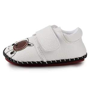 Detail of baby walking shoes with cartoon puppy face and textured white leather