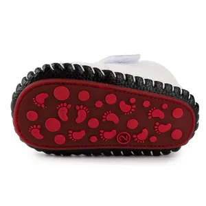 Detail of baby walking shoe with red anti-slip rubber sole and footprint pattern