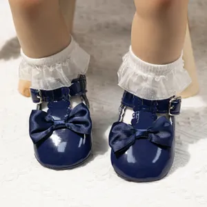 Detail von dunkelblauen Baby-Lackschuhen mit Satinschleife und weißen Spitzensocken
