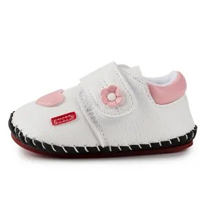 Close-up of baby walking shoes with pink heart patch and floral velcro detail