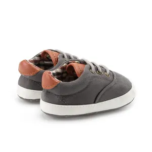 Detail view of baby canvas shoes with gray fabric texture and soft white sole