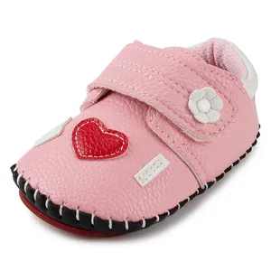 Detailed view of pink toddler shoes with red heart patches and rubber soles