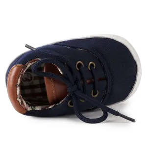 Detailed close-up of dark blue baby canvas shoes with soft soles and plaid lining