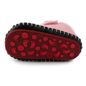 Close-up of pink baby shoes with red non-slip rubber sole featuring cute paw patterns