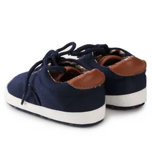 Close-up of baby canvas shoes with dark blue fabric and brown faux leather heel detail