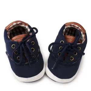 Overhead view of navy blue canvas baby shoes with brown trim and soft soles