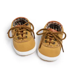 Detail of yellow canvas baby shoe with soft rubber sole and checkered inner lining