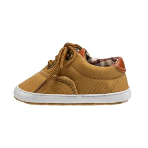 Detail of mustard yellow canvas baby shoes with soft white rubber sole and brown laces