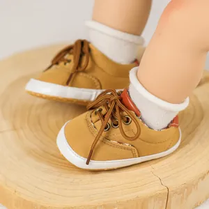 Detailed view of yellow canvas baby shoes with brown laces on a natural wood stand