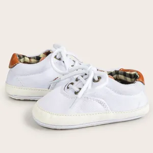 Close-up of white canvas baby walking shoes with plaid lining and brown leather heel tab