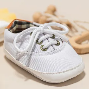 Detail of baby canvas sneakers featuring bronze metal eyelets and classic plaid lining